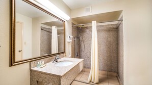 A bathroom with a granite sink, a large mirror, a shower with a glass door, and a towel rack. - Quality Inn Columbia Airport (West Columbia)