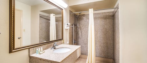 A bathroom with a granite sink, a large mirror, a shower with a glass door, and a towel rack.