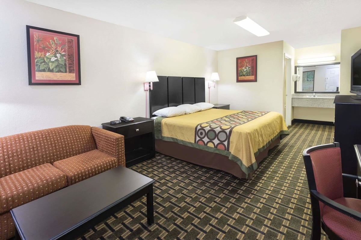 A hotel room with a bed, a sofa, a desk, and a mirror.