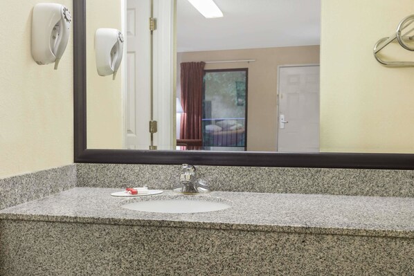 A bathroom with a granite countertop, a sink, and a mirror.