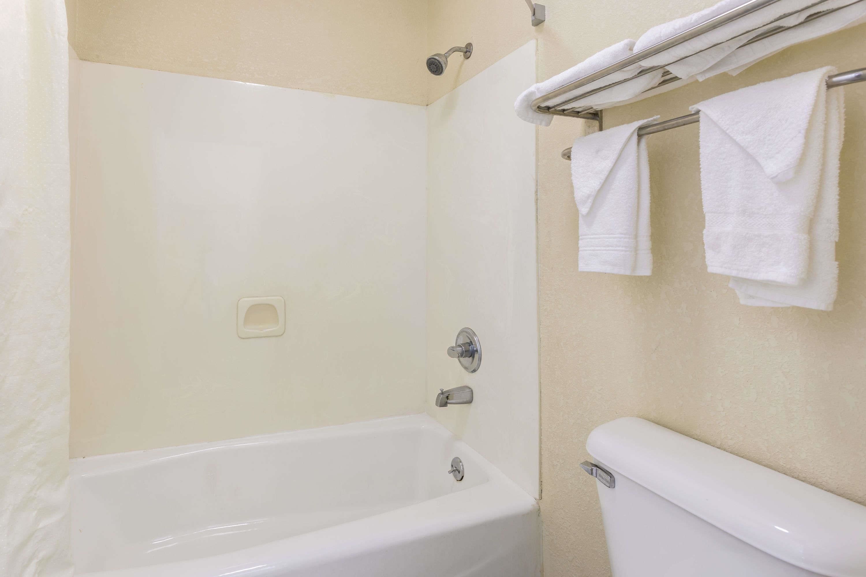 A bathroom with a bathtub, a toilet, and a towel rack with towels.