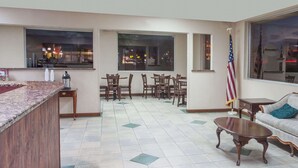 A hotel lobby with a reception desk, seating area, and large windows offering city views. - Knights Inn Lebanon (Lebanon)