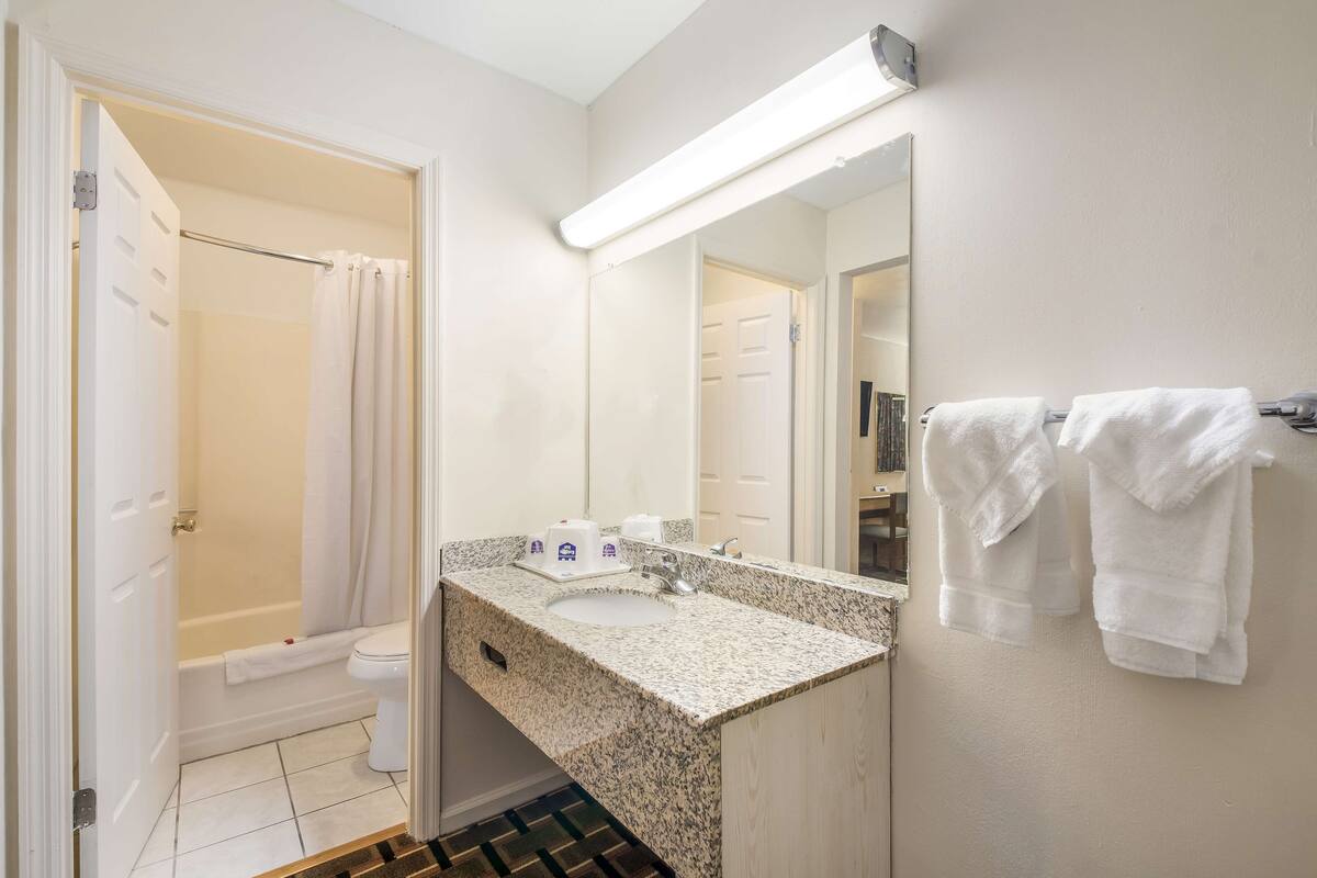 Un baño con lavamanos, espejo y toallas.