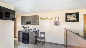 A compact kitchen with granite countertops, a refrigerator, and a microwave. A chair is placed near the counter, and a small potted plant is visible on the floor. - Knights Inn Cleveland, TN (Cleveland)