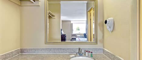 Un baño con encimera de granito, lavabo, espejo y secador de manos.
