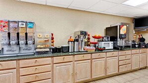 A breakfast bar with various food dispensers, a coffee machine, and a microwave. - Ramada by Wyndham Baltimore West (Catonsville)