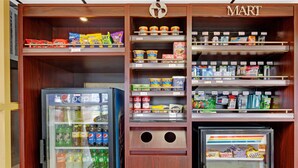 A self-service beverage machine with various drink options and a refrigerated display case with snacks. - Ramada by Wyndham Baltimore West (Catonsville)