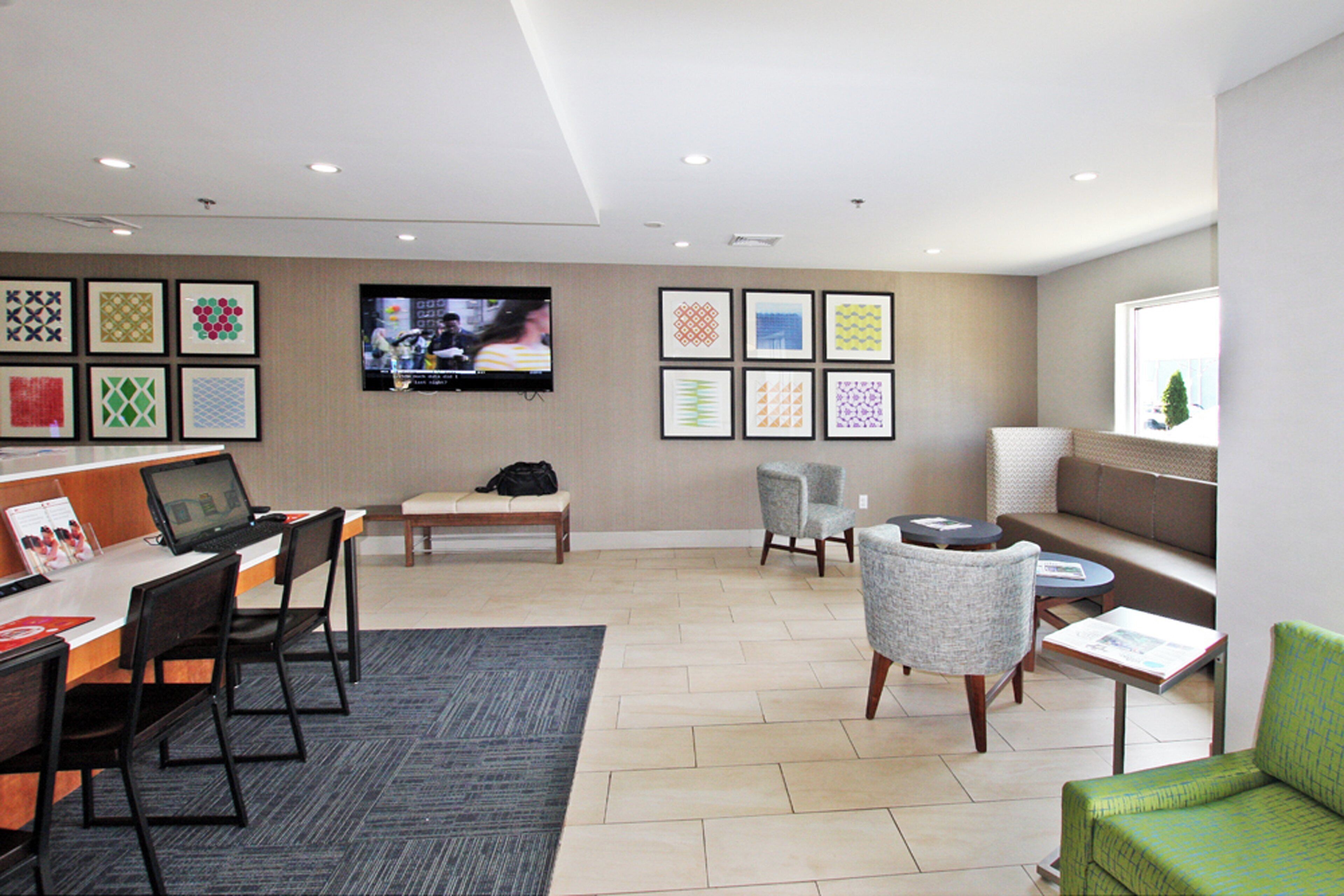 A modern hotel lobby with a reception desk, seating area, and artwork on the walls.