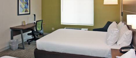 Habitación de hotel con cama, escritorio, silla, lámpara y ventana.
