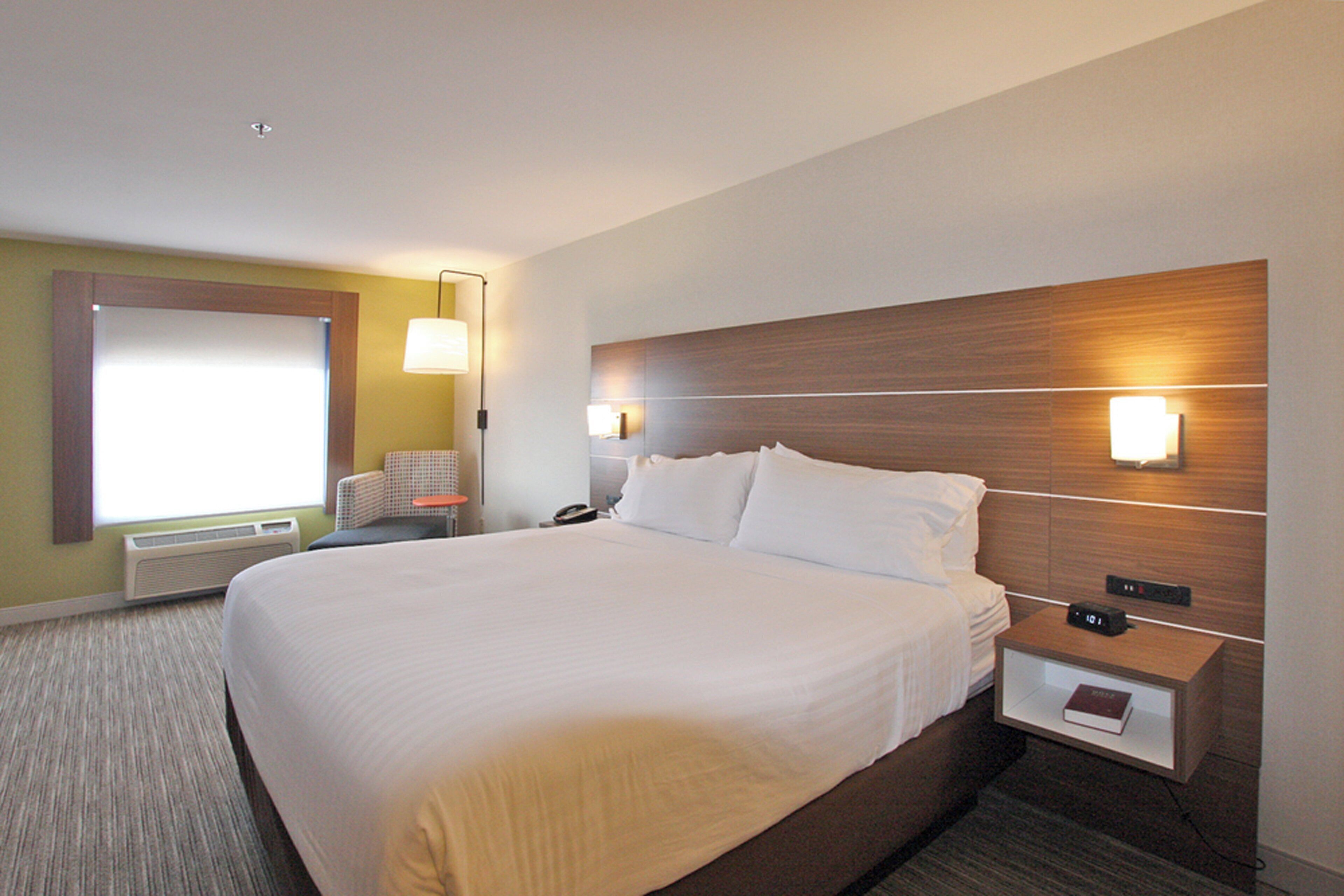 Habitación de hotel con una cama grande, lámparas de noche, una mesita de noche y una ventana con persianas.