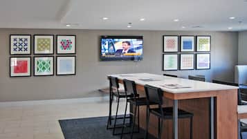 A conference room with a long table, chairs, a flat-screen TV mounted on the wall, and framed geometric patterns on the walls.