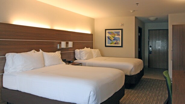 A hotel room with two beds, a wooden headboard, a framed picture on the wall, and a door in the background. - Holiday Inn Express Branford-New Haven by IHG (Branford)