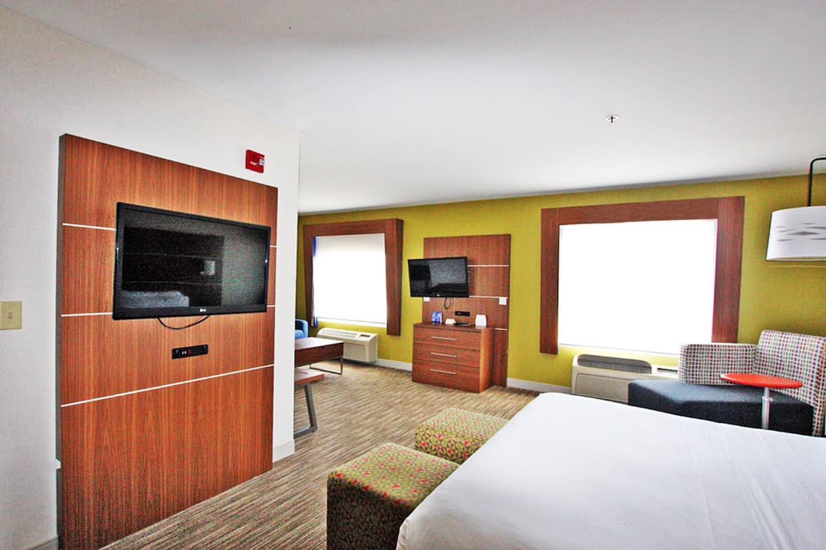 A hotel room with a bed, a desk, a television, and a window.