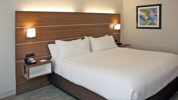 A hotel room with a large bed, bedside lamps, a nightstand with a phone, and a framed picture on the wall.