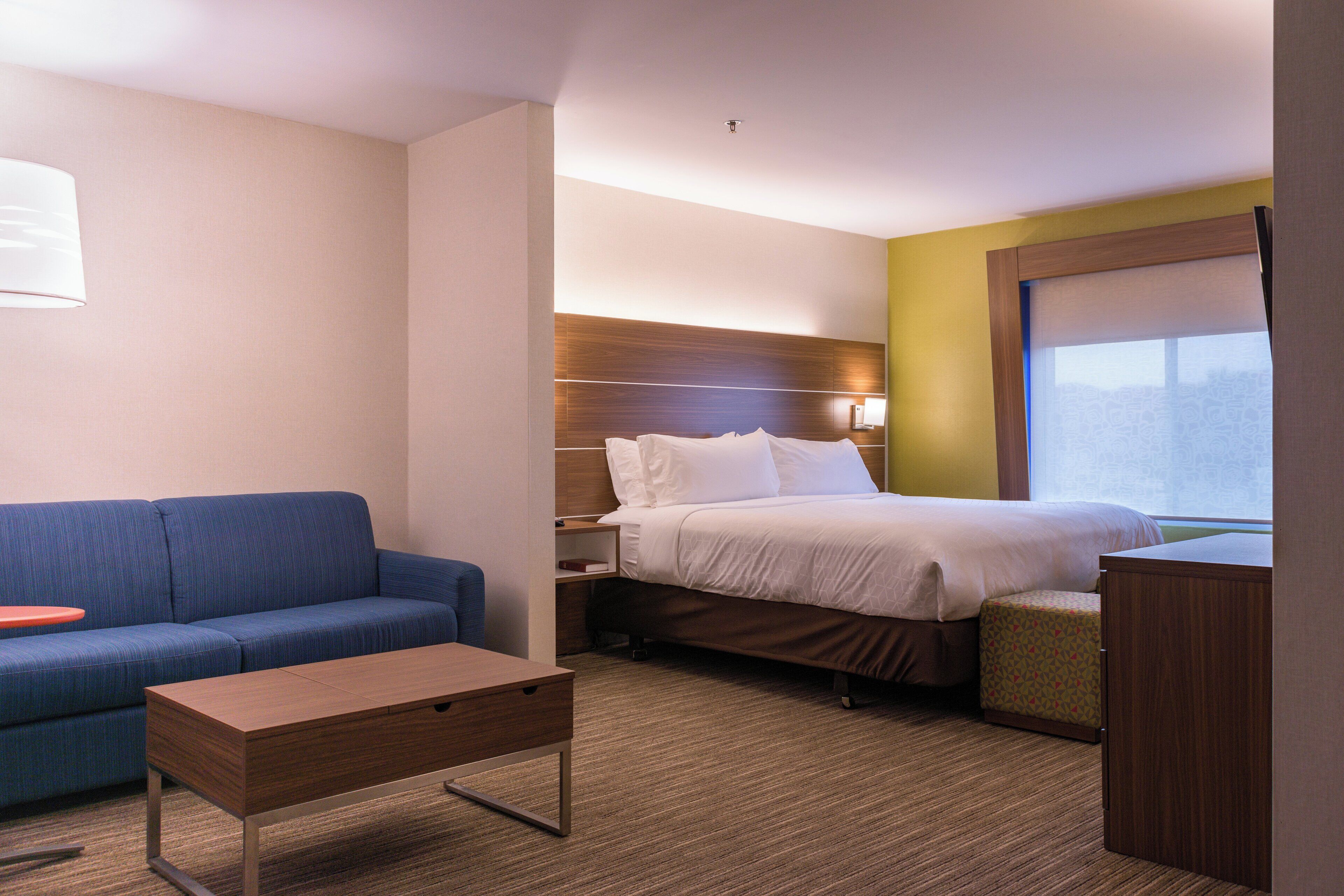 Una habitación de hotel con una cama, un sofá, una mesita y una mesita de noche.