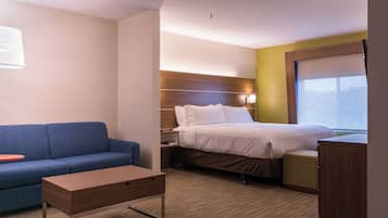 Una habitación de hotel con una cama, un sofá, una mesita y una mesita de noche.