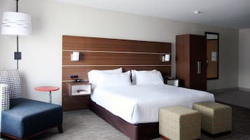 A hotel room with a large bed, a nightstand, a desk, a chair, and a wardrobe.