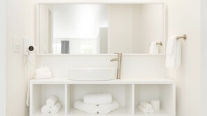 A modern bathroom with a large mirror, a white sink, and shelves holding towels and toiletries. - Oneway Brunswick (Brunswick)