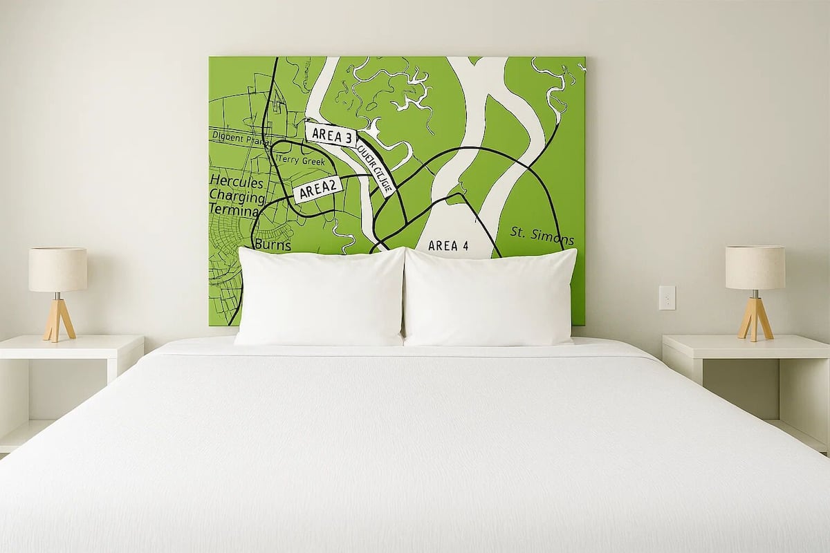 A bed with white bedding, two white pillows, and a green map with labeled areas on the wall behind it.