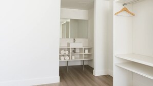 A modern, white bathroom with a vanity, shelves, and a hanging shower rod. - Oneway Brunswick (Brunswick)