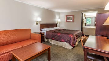 A hotel room with a bed, a sofa, a table, and a desk.