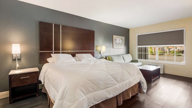 A bedroom with a large bed, bedside tables, a nightstand, a window with a view, and a headboard with a light fixture. - SureStay Hotel by Best Western Sarasota Lido Beach (Sarasota)