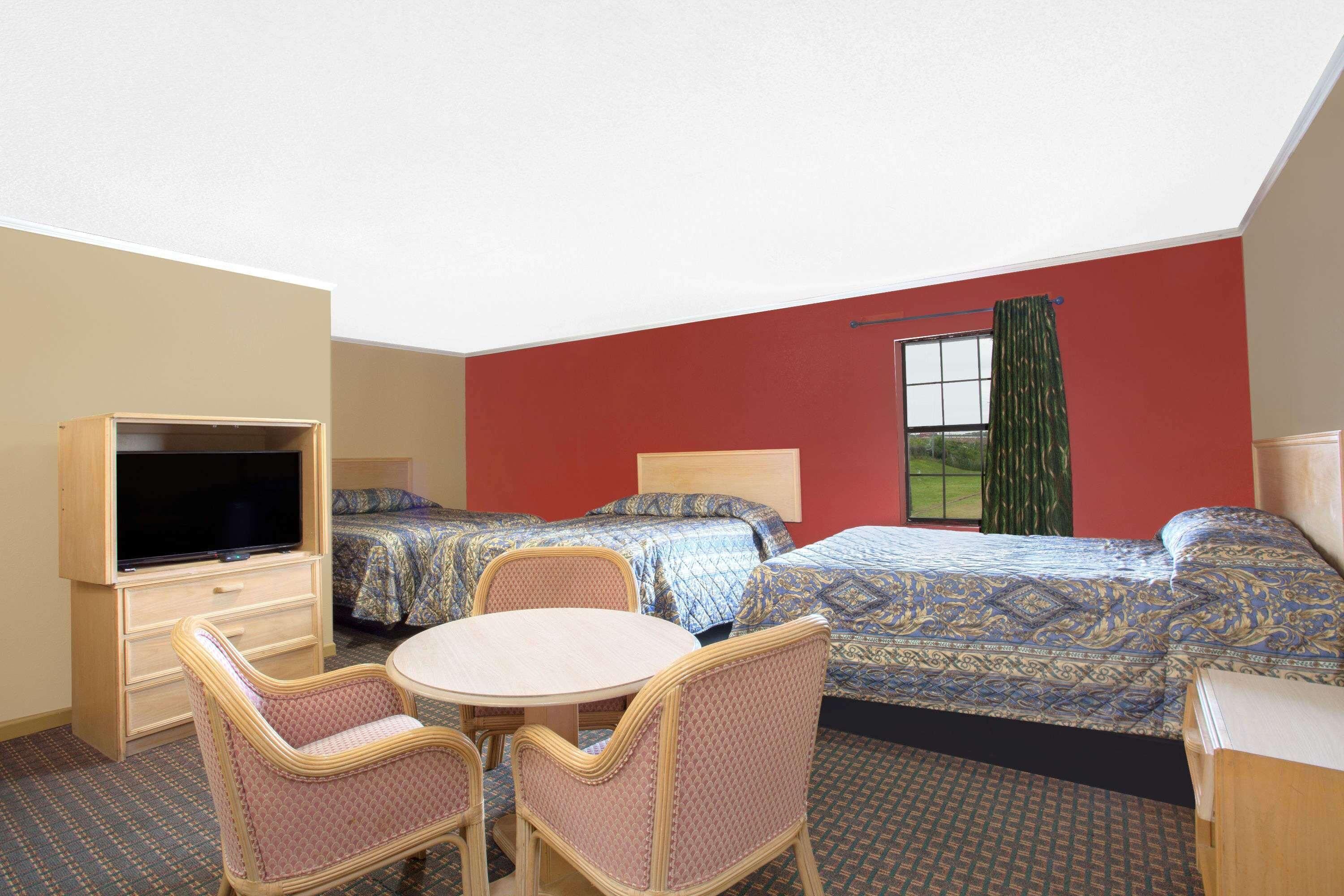 A hotel room with two beds, a TV, a table, and chairs.