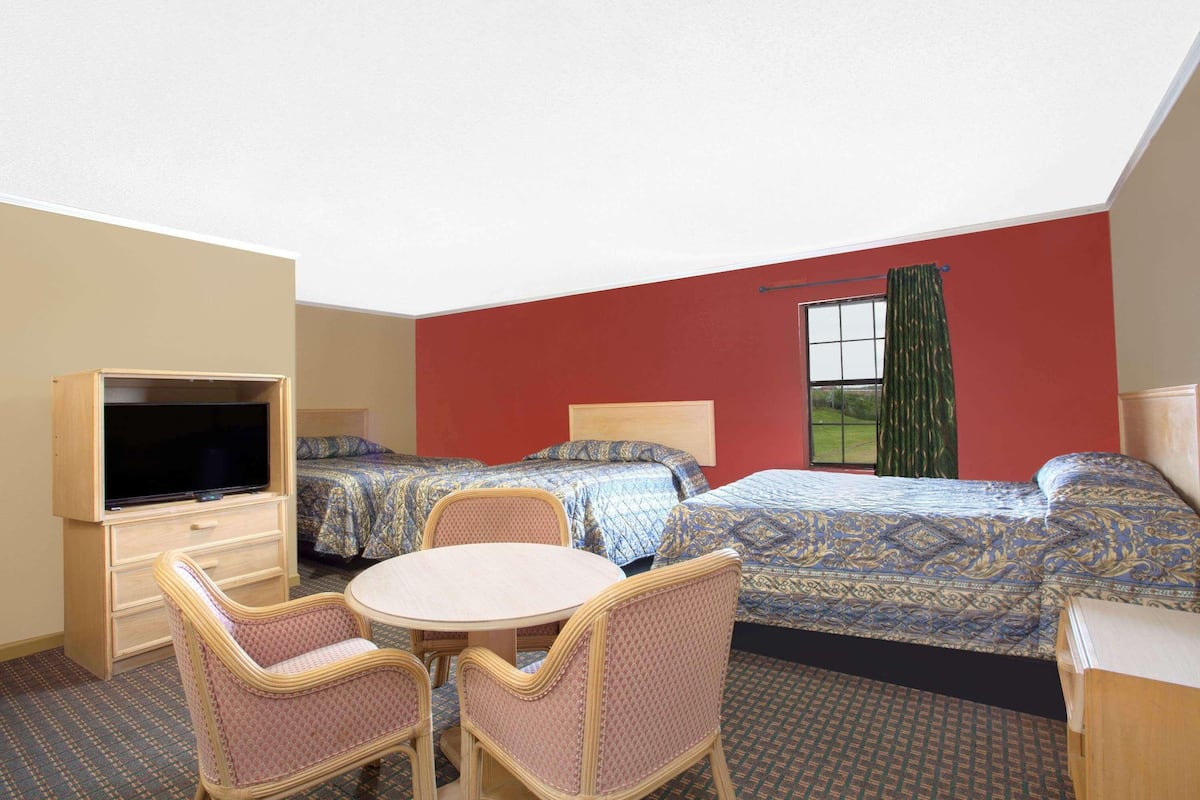 A hotel room with two beds, a TV, a table, and chairs.