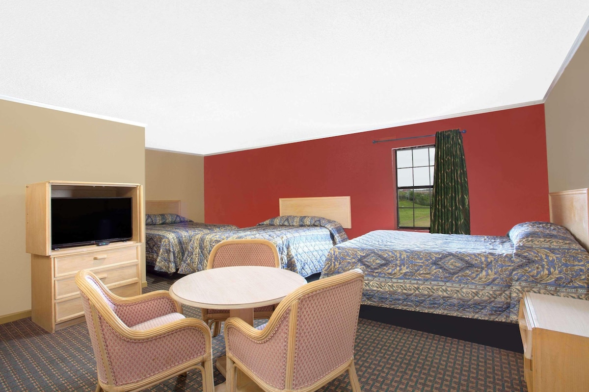 A hotel room with two beds, a TV, a table, and chairs.