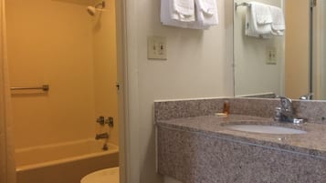 A bathroom with a shower, toilet, sink, and a mirror.
