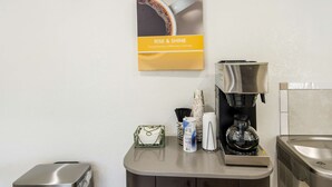 A coffee station with a coffee machine, disposable cups, and a coffee pod dispenser. - Motel 6 Salem, VA (Salem)