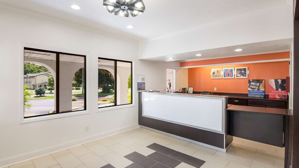 A reception area with a counter, large windows, and a modern ceiling light. - Motel 6 Salem, VA (Salem)