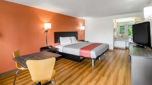 A hotel room with a bed, bedside tables, a desk, a chair, a television, and a bathroom visible through an open door. - Motel 6 Salem, VA (Salem)