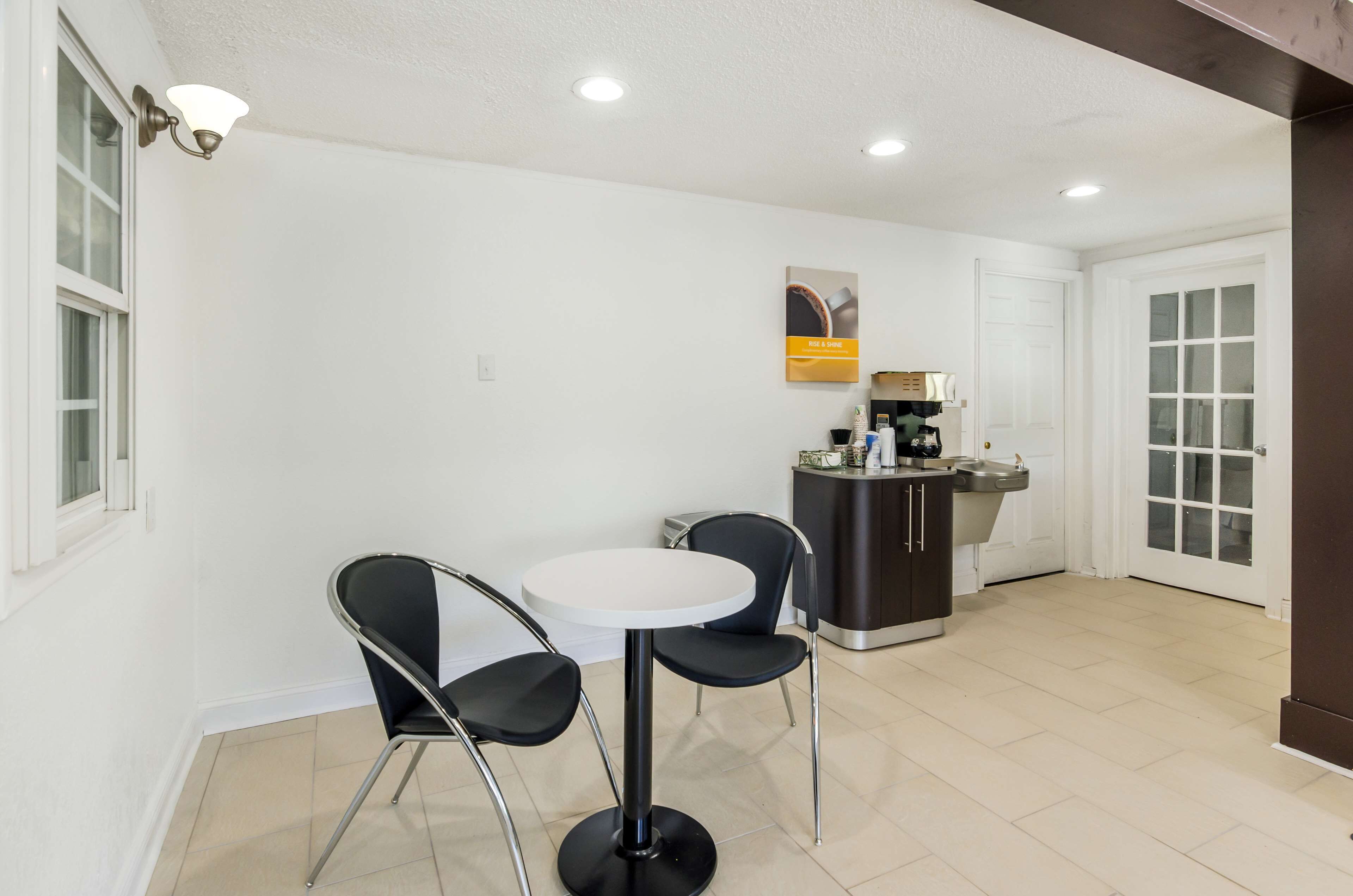 Una cocina compacta con una mesa blanca y dos sillas, una pequeña barra y un refrigerador.