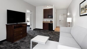 Una sala de estar moderna con un televisor de pantalla plana, una mesa de centro blanca y un sofá gris.