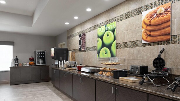 Una cocina moderna con una encimera larga, varios electrodomésticos y un salpicadero de azulejos.