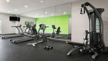 Une salle de sport équipée de tapis de course, d’appareils de musculation et d’haltères.