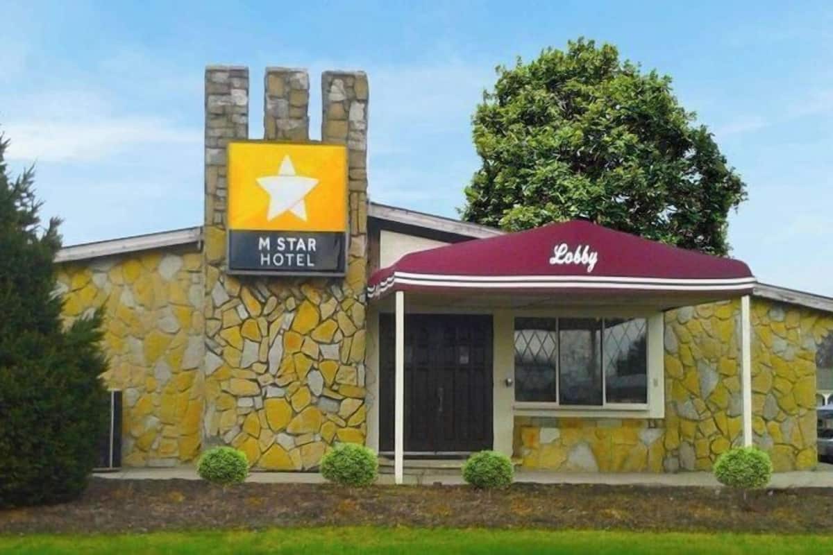 A M Star Hotel with a stone facade, a yellow sign with a white star, and a maroon 'Lobby' tent.