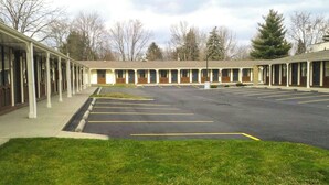 A motel with a row of rooms, a parking lot, and a grassy area in front. - M Star Columbus North (Columbus)