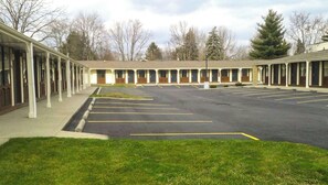 Un motel avec une s érie de chambres, un parking et une pelouse devant.
