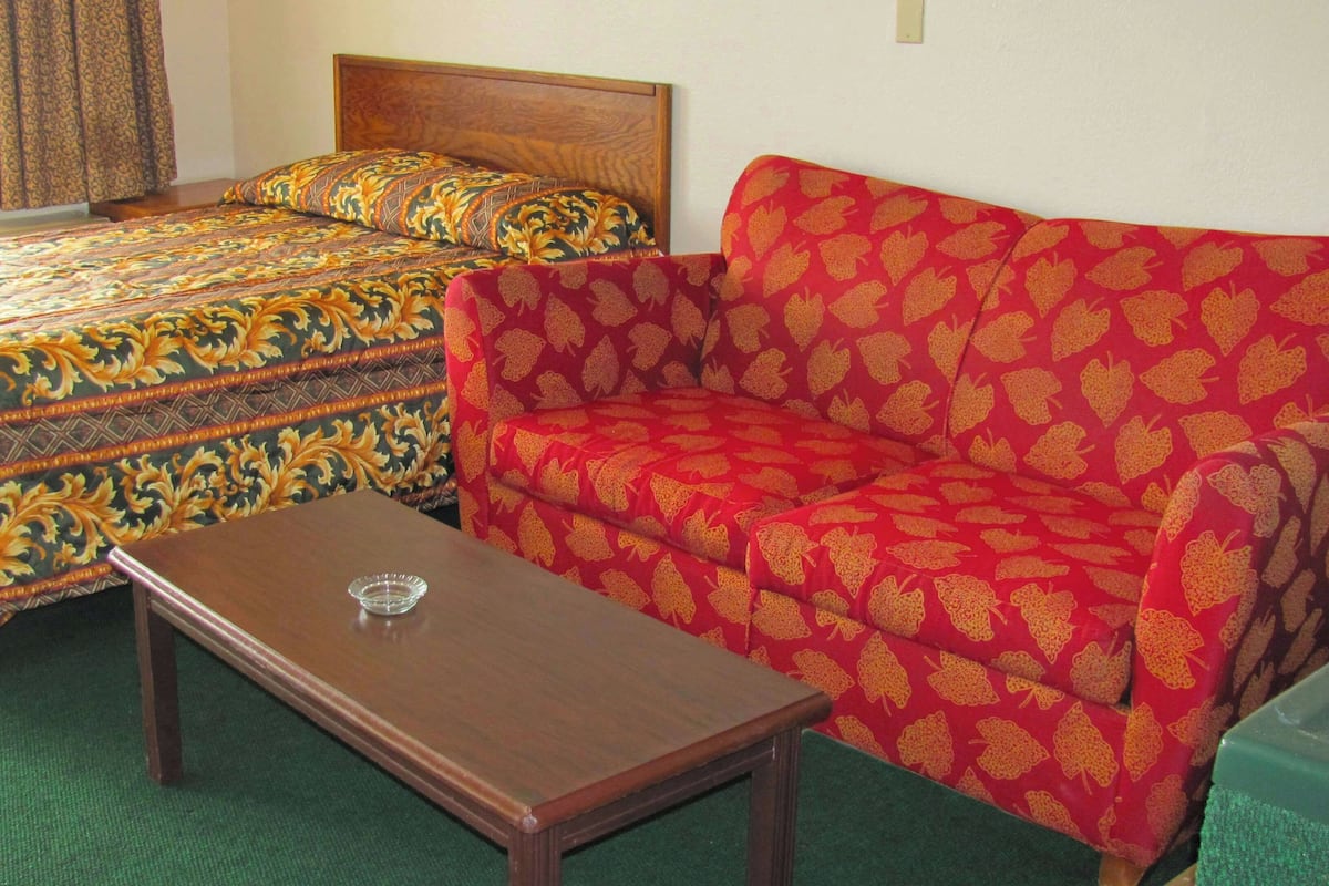 A room with a bed, a sofa, and a small table.