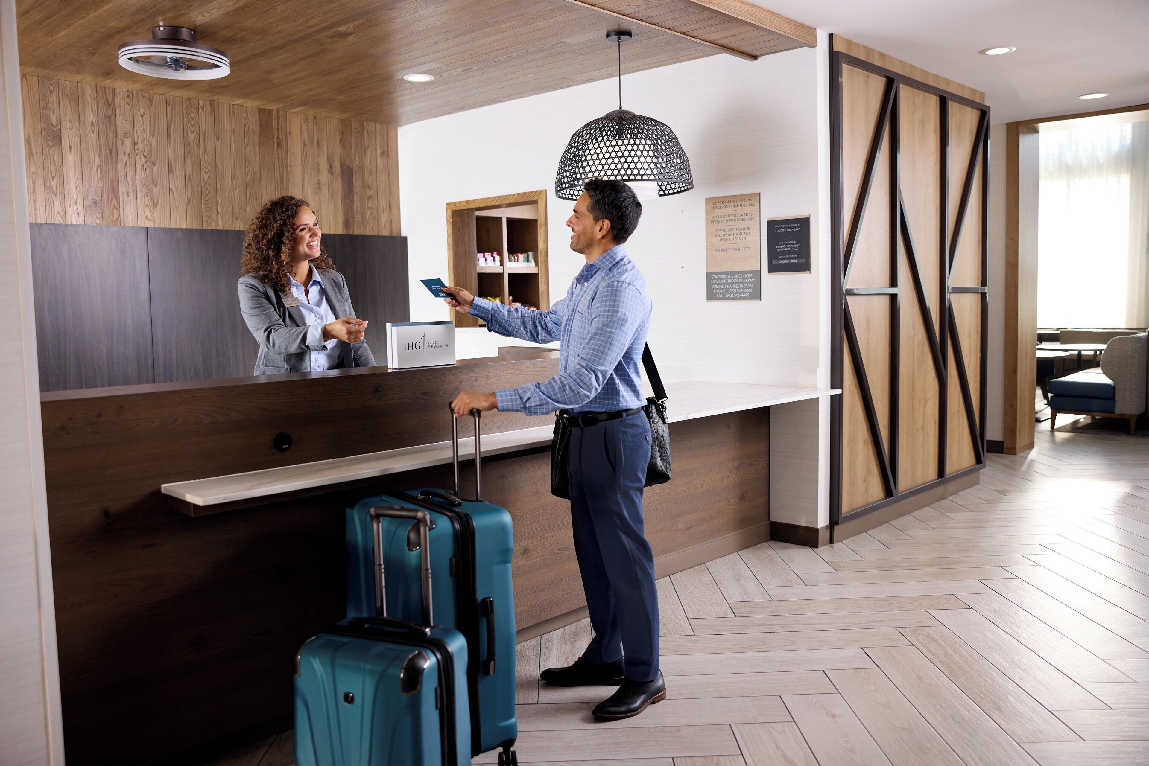A reception desk with a wooden panel wall, a hanging pendant light, and a counter with a sign.