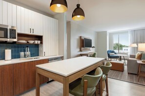 A modern kitchen with a dining area, a flat-screen TV, and a seating area with a view.