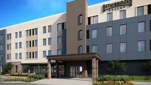 A modern hotel with a flat roof, multiple windows, and a sign reading "STAYBRIDGE SUITES". - Staybridge Suites Detroit Woodhaven by IHG (Woodhaven)