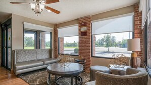 A modern interior with a sectional sofa, round coffee table, and wicker chairs. - Best Western Muncie (Muncie)