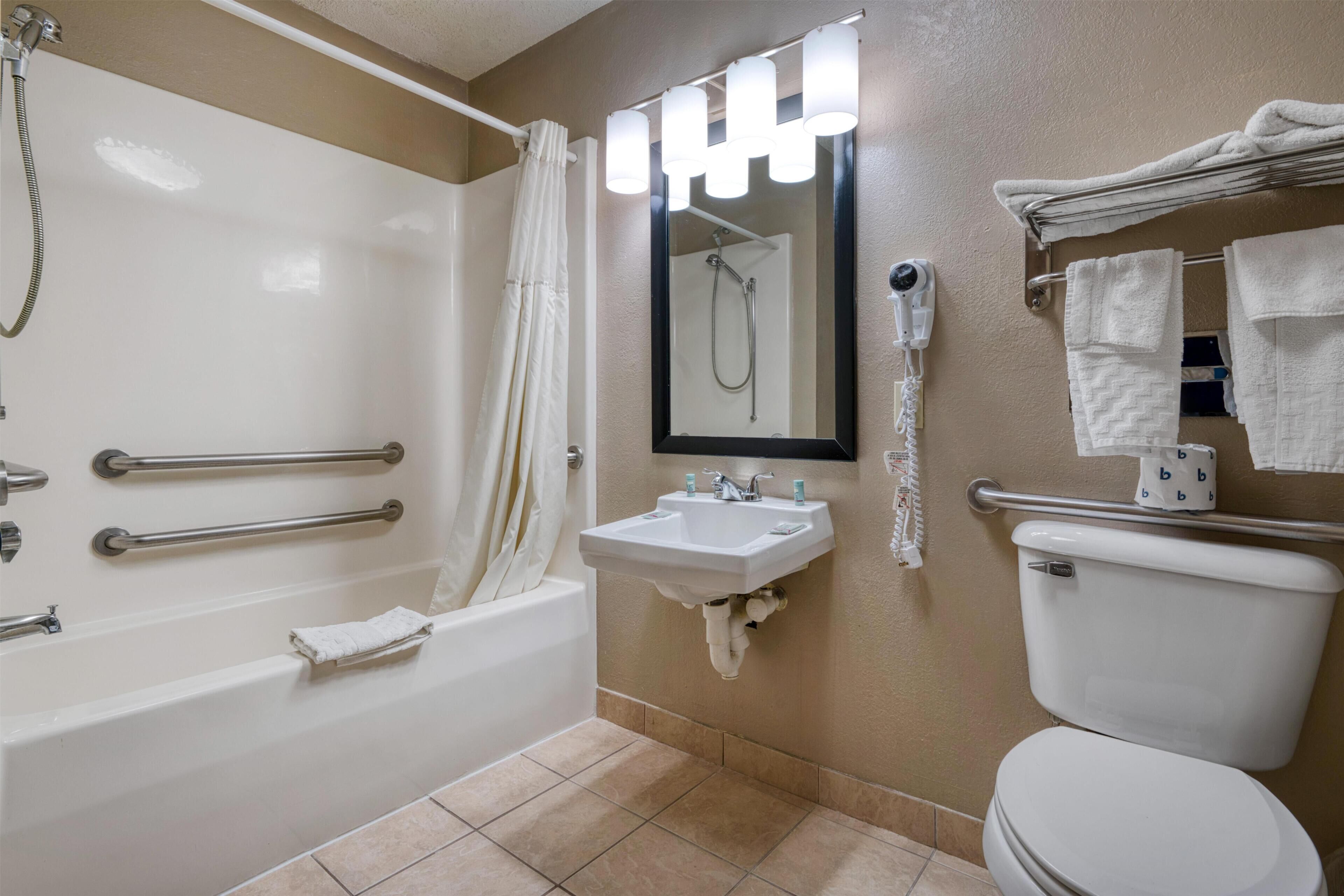A bathroom with a bathtub, a sink, a toilet, a shower, and a hairdryer.