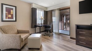 A hotel room with a sofa, a desk with a chair, a television, and a window with curtains. - Best Western Muncie (Muncie)
