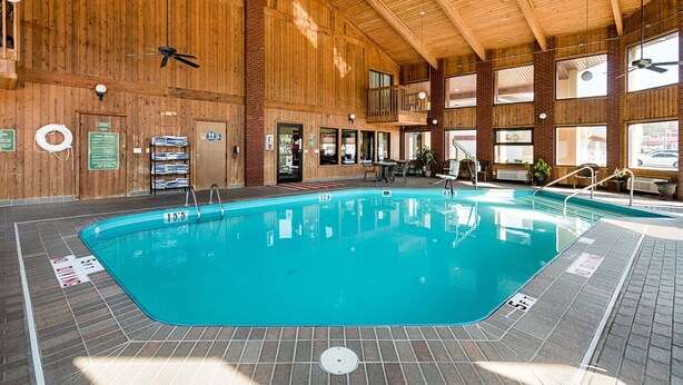 An indoor swimming pool with wooden walls and a tiled floor, surrounded by windows and a mezzanine level. - Quality Inn Parkersburg North - Vienna (Parkersburg)