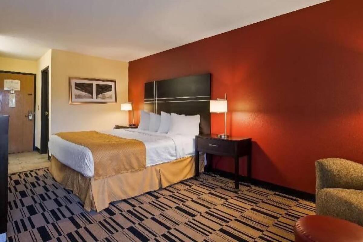 Une chambre d’hôtel comprenant un lit, deux tables de chevet, un bureau, une chaise et un téléviseur.