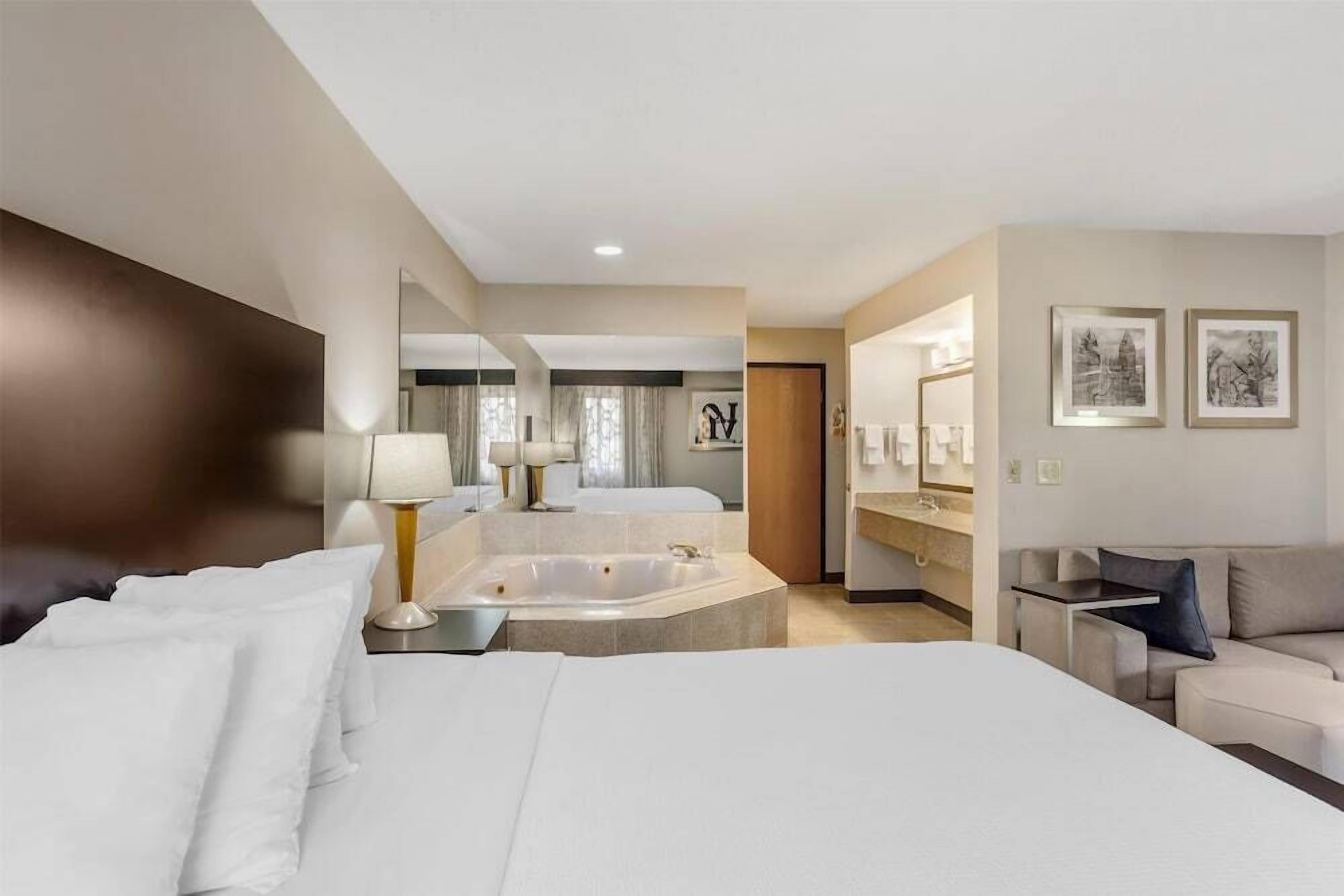 Ein Hotelzimmer mit einem großen Bett, einer Badewanne, einer Sitzecke mit einer Couch und einem kleinen Tisch.